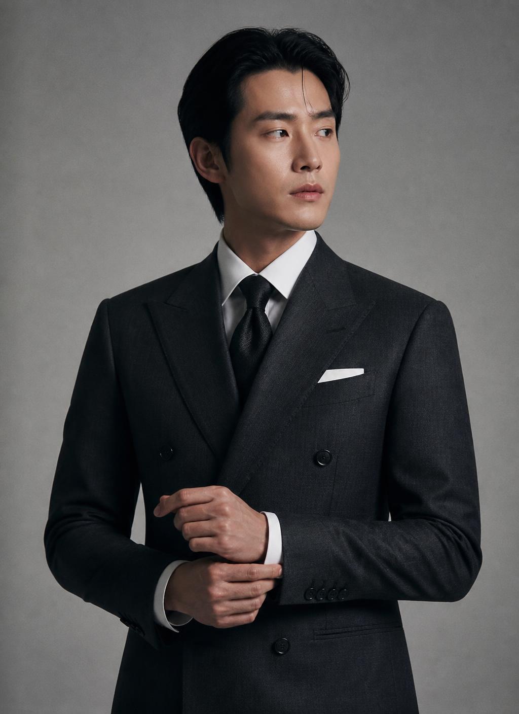 Man in a charcoal double-breasted bespoke suit adjusting his cuff